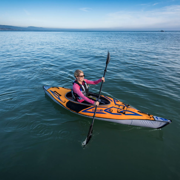 Woman paddling a kayak on calm water during an in-water demo session.