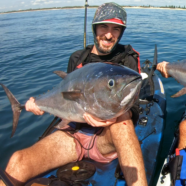 Angler holding a tuna on a fishing kayak during a guided kayak fishing lesson.