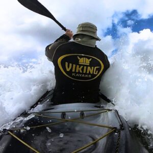 Rear view of viking kayaks shirted paddler, jason milne, aka paddle guy, riding into the waves on a viking espri