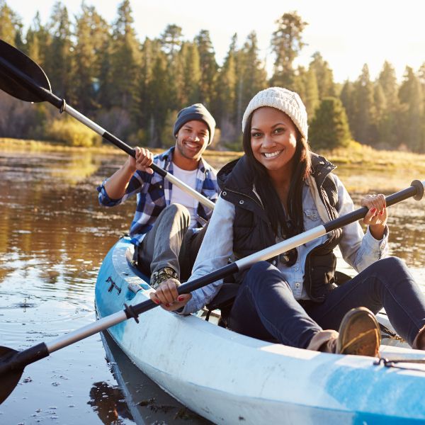 Couple kayaking while smiling at a drone and water-level camera