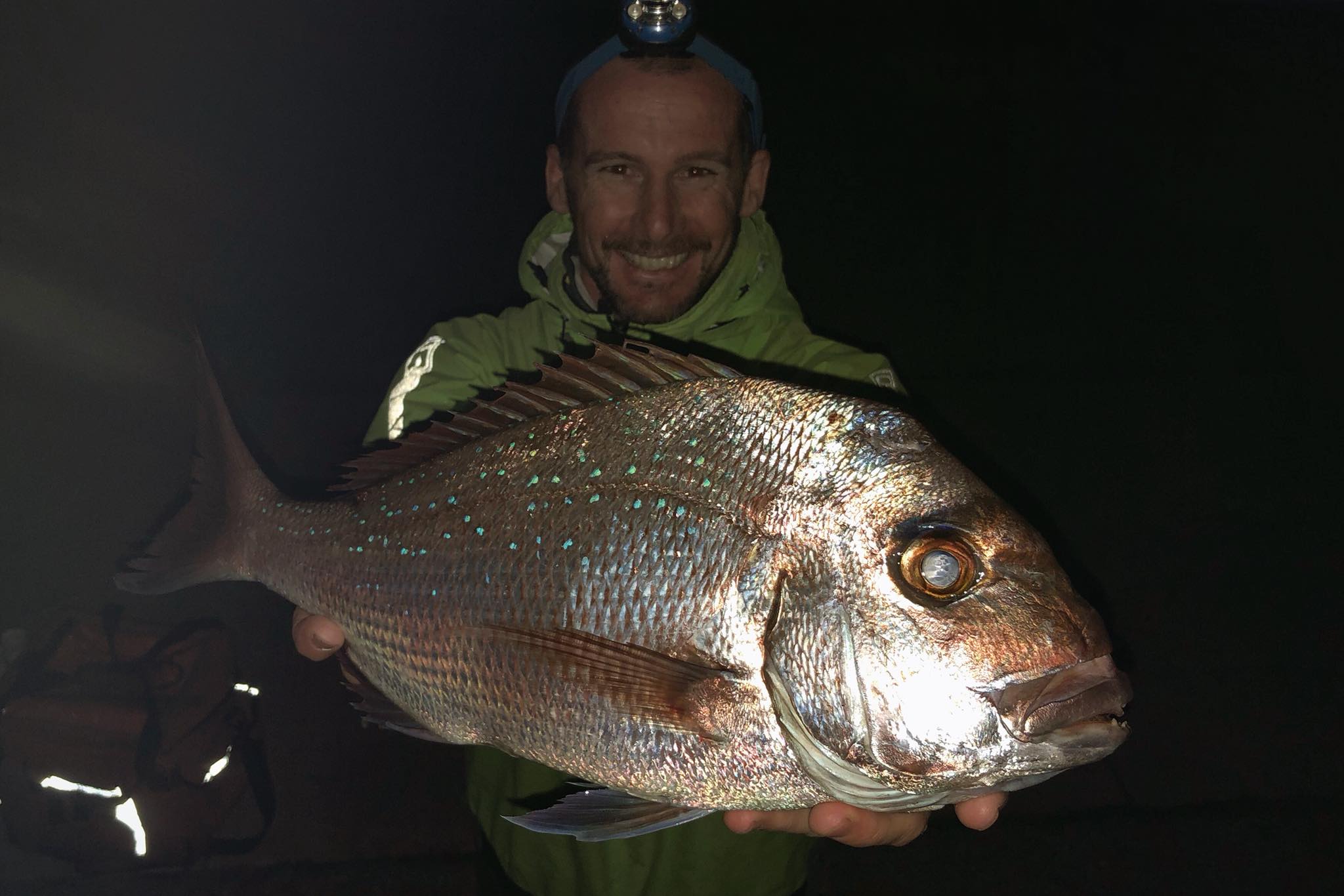 Kayak angler jason milne, aka paddle guy holding a freshly caught snapper on a kayak at sea